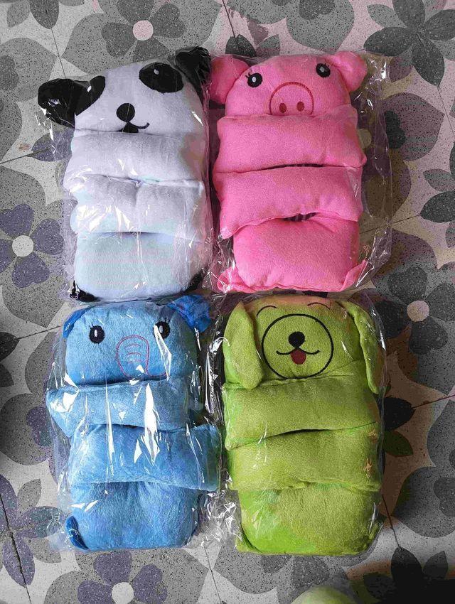 Colorful plush animal pillows including panda, pig, bear, and dog, wrapped in plastic on floral tile